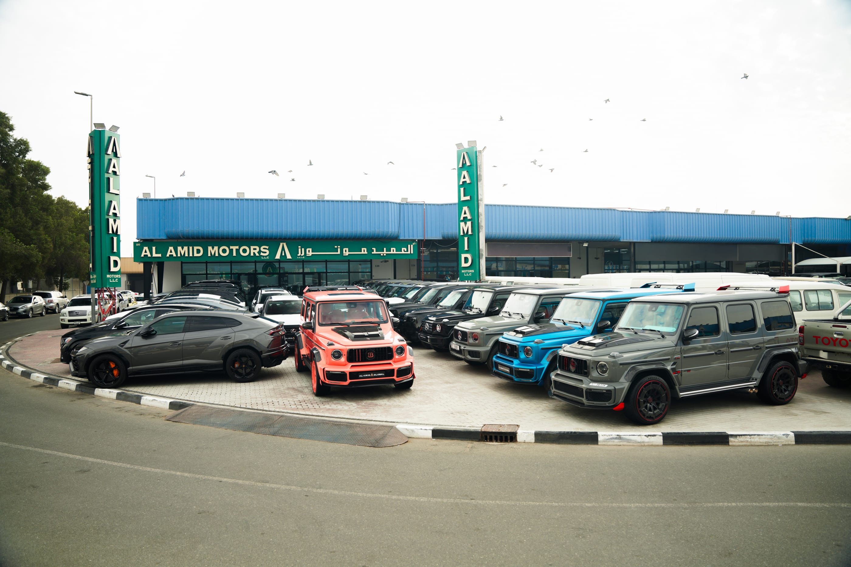 Al Amid Motors showroom in Dubai — Brabus G-Class, Mercedes G 63 and Lamborghini Urus on the forecourt